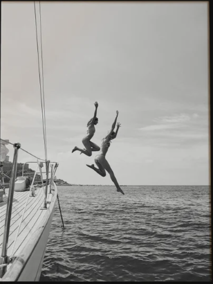 Black and white artwork of two people jumping from a boat into the sea
